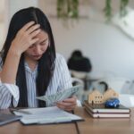 Woman reviewing cash and monthly bills to determine if her large family meets Florida Chapter 7 bankruptcy means test income limits.