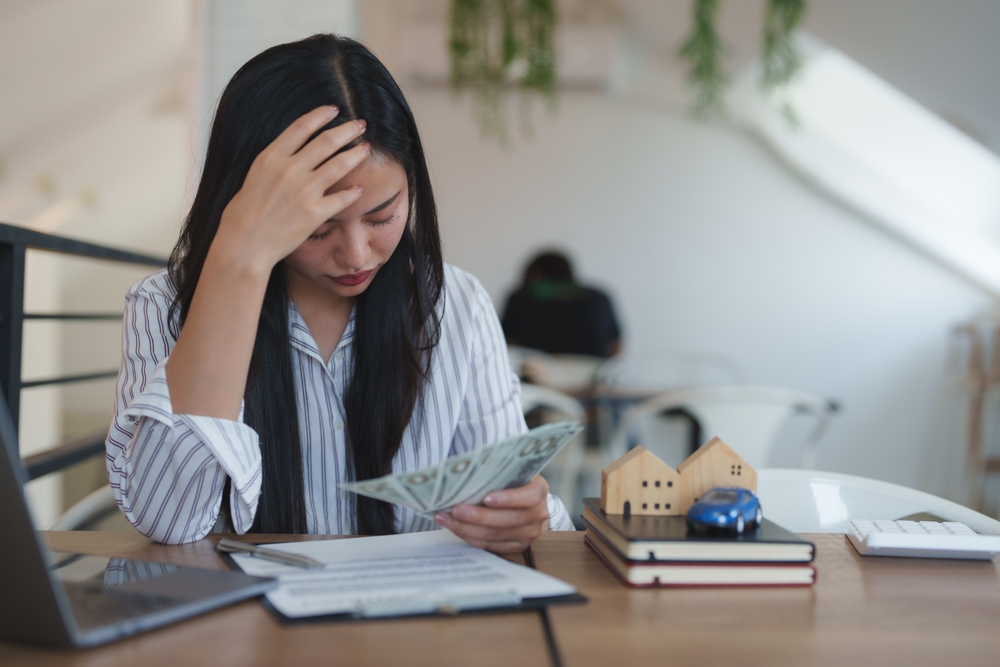Woman reviewing cash and monthly bills to determine if her large family meets Florida Chapter 7 bankruptcy means test income limits.